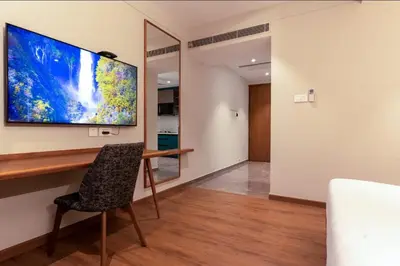 a room with a desk and a large tv on the wall at Seashell Apartments in Kozhikode