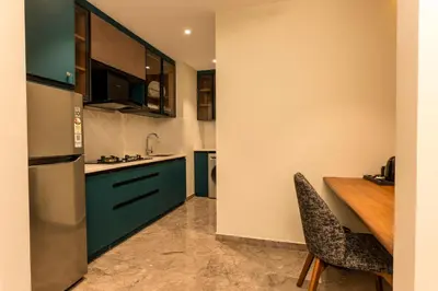 a kitchen with blue cabinets and a wooden table at Seashell Apartments in Kozhikode
