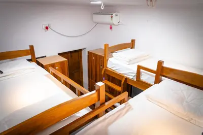 a dorm room with three beds and a air conditioner at Leo Vishroam in Mysore