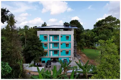 an apartment building with blue windows and trees at Vajra Periyar Heritage in Alwaye