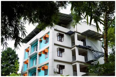 a white apartment building with balconies and trees at Vajra Periyar Heritage in Alwaye