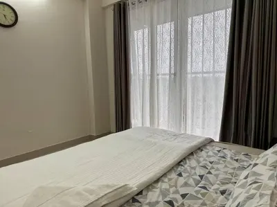 a bed in front of a window with a clock at Memmsta Blooming Bird Guruvayur in Guruvāyūr