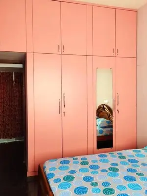 a bedroom with pink cabinets and a bed and a mirror at NJM Villa in Coimbatore