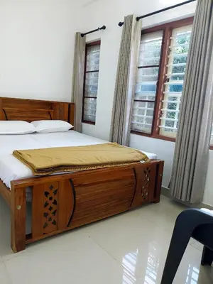 a bedroom with a large wooden bed in front of a window at Nature's View Service Villa in Vythiri