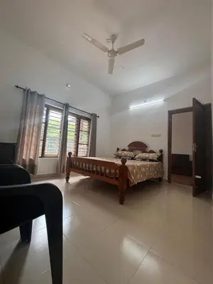 a bedroom with a bed and a ceiling fan at Nature's View Service Villa in Vythiri