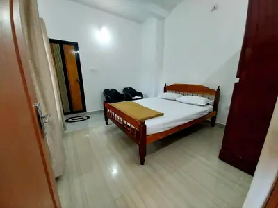 a bedroom with a bed with white sheets and a wooden floor at Nature's View Service Villa in Vythiri