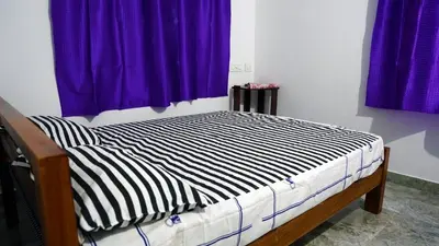 a bed in a room with purple curtains at Prakruthi Home stay in Kanjikode