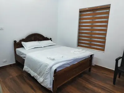 a bedroom with a bed with white sheets and a window at Roneys Villa in Wayanad