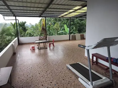 a room with a gym with a treadmill and a bench at Roneys Villa in Wayanad