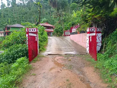 a dirt road with red gates on the side of a mountain at Abiraksha Stay Coorg in Madikeri