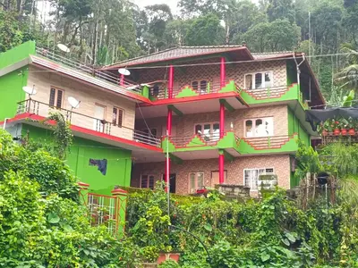 a green building with balconies on the side of it at Abiraksha Stay Coorg in Madikeri