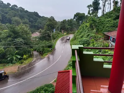 a winding road on a hill with a car on it at Abiraksha Stay Coorg in Madikeri