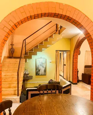 a dining room with a wooden table and a staircase at Boughn Villa in Kozhikode