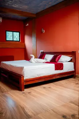 a bedroom with a large bed with red walls at Beehive staycations in Ambalavayal