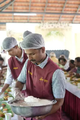two men in red uniforms preparing food in a kitchen at Beehive staycations in Ambalavayal