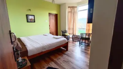 a bedroom with green walls and a bed and chairs at Dwarka Home Stay in Ooty