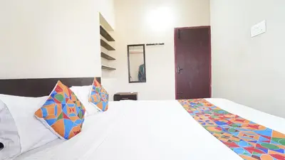 a bedroom with a white bed with colorful pillows at Hotel Varun 1 bhk in Coimbatore