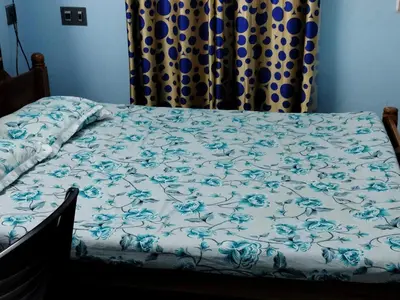 a bed with a blue and white comforter at Beautiful and Peaceful house in Kanjikode