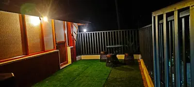 a balcony with chairs and a table at night at Homestay Rooms Muzhakkunnu Near Kannur International Airport in Iritti