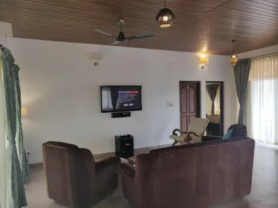 a living room with a couch and a tv on the wall at The Elegant homes in Kushālnagar
