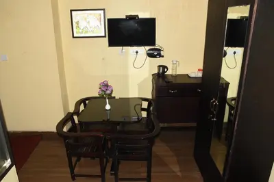 a table and chairs and a desk and a television at Ghala Residency in Munnar