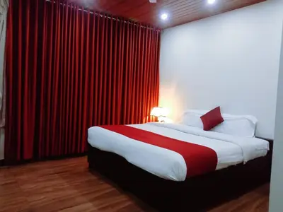 a bedroom with a large bed with red curtains at Ghala Residency in Munnar