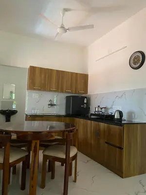 a kitchen with wooden cabinets and a table with a dining room at Gaya beach hacienda in Irimbranallūr