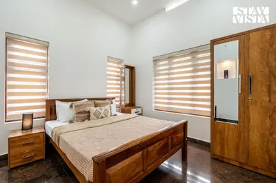 a bedroom with a bed and two windows at Stayvista at Whitewood Serene 5BHK Homestay - Wayanad in Wayanad