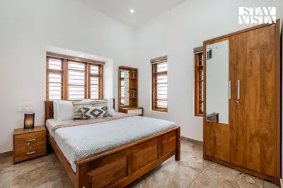 a bedroom with a bed and a wooden door at Stayvista at Whitewood Serene 5BHK Homestay - Wayanad in Wayanad