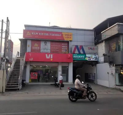 a person riding a motorcycle in front of a store at Regent Tourist Home in Palakkad