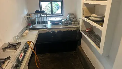 a kitchen with a sink and a stove in it at Tharavadu Homestay in Athirappilly