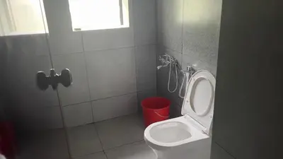 a bathroom with a toilet and a red trash can at Tharavadu Homestay in Athirappilly