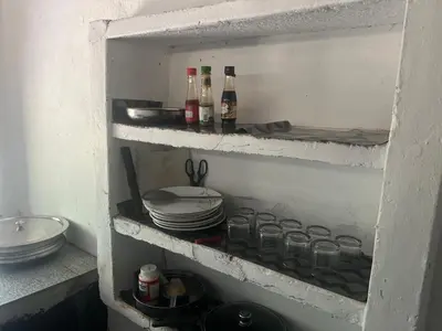 a shelf with plates and wine bottles and dishes at Tharavadu Homestay in Athirappilly