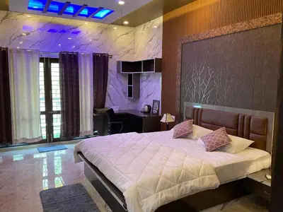 a bedroom with a large bed and a desk in it at Kings Villa Mysore in Mysore
