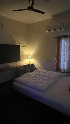 a bedroom with a bed with a ceiling fan at Kings Villa Mysore in Mysore