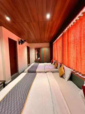 a row of beds in a room with a wooden ceiling at City Palace Hotel in Ooty