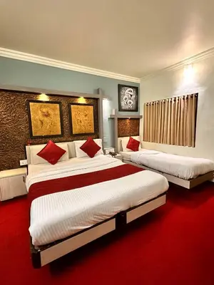 two beds in a hotel room with red carpet at City Palace Hotel in Ooty
