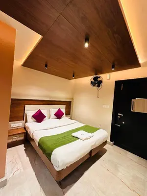 a bedroom with a large bed with purple and green sheets at City Palace Hotel in Ooty