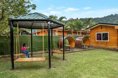 a woman sitting on a swing in a gazebo at StayVista at The Woodscapes with Lawn & Views in Ooty