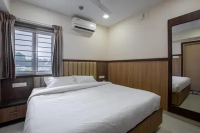 a bedroom with a white bed and a window at Hotel PRM Aruna Archadia in Erode
