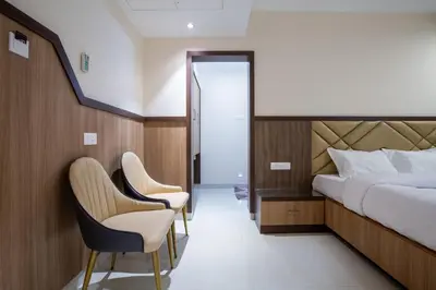a hotel room with a bed and two chairs at Hotel PRM Aruna Archadia in Erode