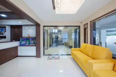 a lobby with a yellow couch and a fish tank at Hotel PRM Aruna Archadia in Erode