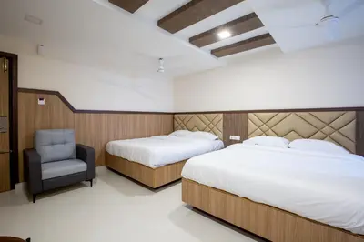 a hotel room with two beds and a chair at Hotel PRM Aruna Archadia in Erode