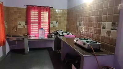 a kitchen with a counter with a stove in it at Keerthis Home Stay in Madikeri