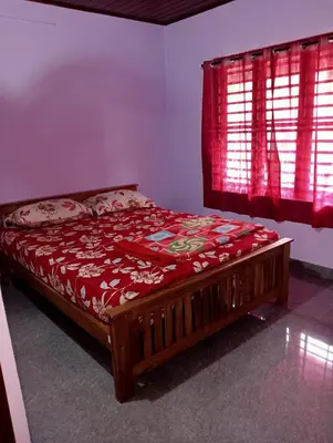 a bed in a room with a red window at Keerthis Home Stay in Madikeri