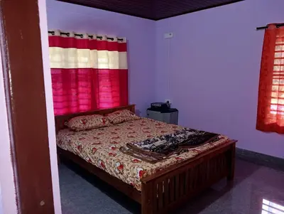 a bedroom with a bed with a red curtain at Keerthis Home Stay in Madikeri