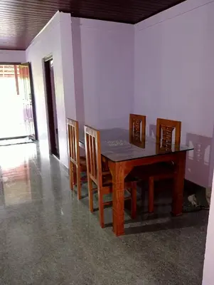 a dining room with a wooden table and chairs at Keerthis Home Stay in Madikeri
