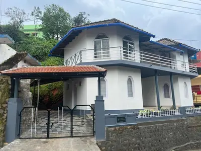 a white and blue house with a gate at Fireflies R in Madikeri