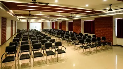 an empty room with chairs in a hall at Sakthi River Resort in Pollāchi