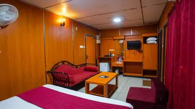 a room with a bed and a couch and a table at Sakthi River Resort in Pollāchi